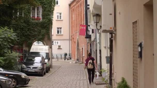 Ruhiger gemütlicher Hof mit geparkten Autos, einsame Passanten, die auf dem steinernen Bürgersteig spazieren gehen — Stockvideo