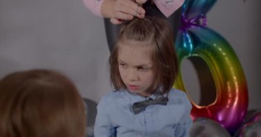 Kutlama için hazırlık. Uzun saçlı bir çocuk saçtan bir topuz olur..