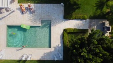 Çocuk havuz güneşinin olduğu açık havuzun kenarından suya atlar..