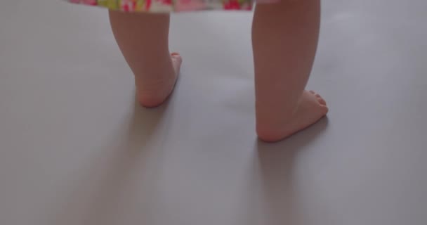 Primeros pasos de un niño con los pies desnudos sobre una superficie gris. Caminar independientemente — Vídeo de stock