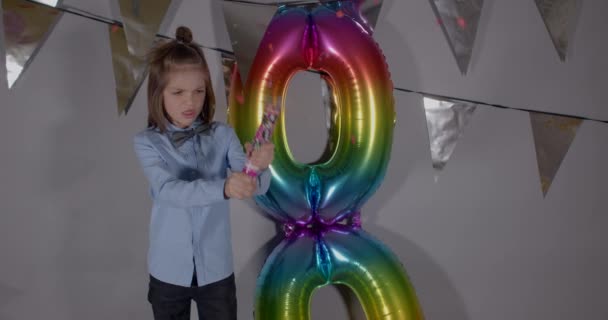 Happy boy blows up a confetti popper at an eighth birthday party decorations. — Stock Video
