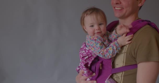 Vader kust het kind, grijze achtergrond ruimte voor tekst. Het dragen van baby in draagdoek — Stockvideo