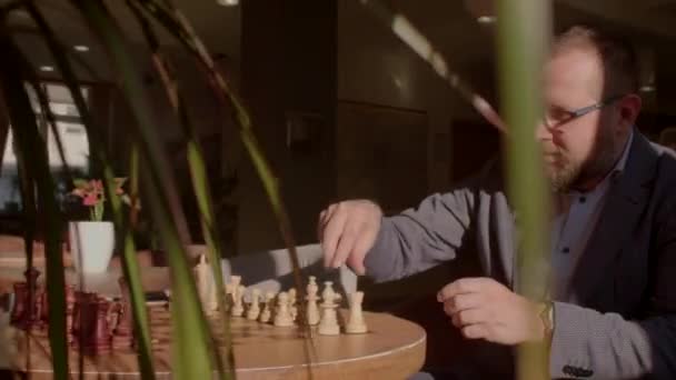 Um homem coloca peças de xadrez no tabuleiro na mesa. Ele põe a ordem certa.. — Vídeo de Stock