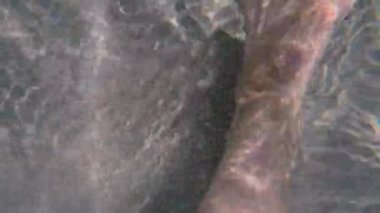 Denizde yalın ayak yürümek, yakın çekim, güneş parlaması. Boş zaman aktiviteleri. 