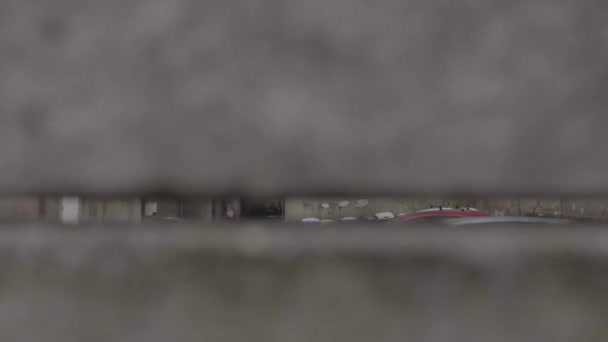 Pengawasan tersembunyi seorang kriminal melalui lubang di dinding jalan abu-abu. Menguntit — Stok Video