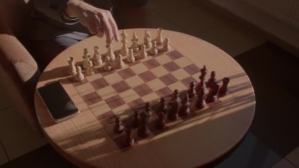 Begin van het schaakspel. Ronde tafel met een telefoon. Mans hand beweegt de cijfers. — Stockvideo