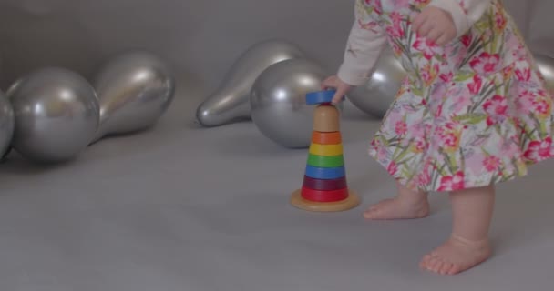 Malá bosá holka hraje na šedém pozadí. Překvapený pohled na dětskou tvář. — Stock video