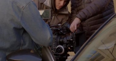 Film ekibi kamerayı kullanıma hazırlıyor. Aktör arabada. Sahne arkası film sahneleri