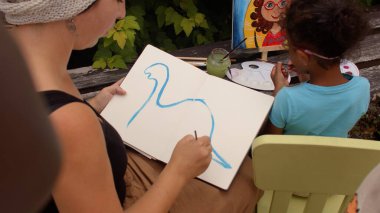 Çocuklar için resim atölyesi. Öğretmen açık havada bir dinozor çizer..