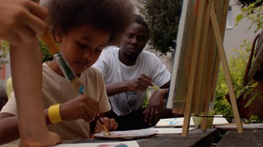 Erkek öğretmenin gözetiminde sanat kampındaki çocuklar için resim atölyesi..