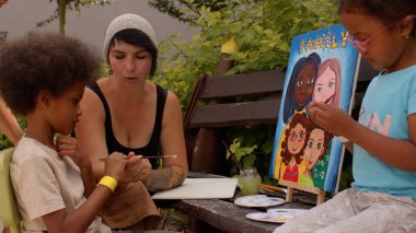 Kadın çocuğa fırçayı doğru düzgün tutmayı, el ve parmak kaslarını geliştirmeyi öğretir.