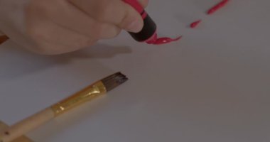 Çocuk eliyle tüp kağıdı kırmızı boyayla boyar.. 
