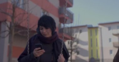 Dikkatini telefonda swing yapan kadına ver. Boş zamanlarını avluda geçiriyor.