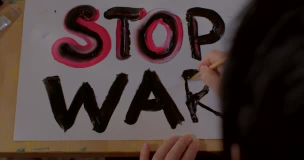 Disegna un manifesto di fine guerra su carta. La mano dei bambini tiene un pennello, fa una lettera. — Video Stock
