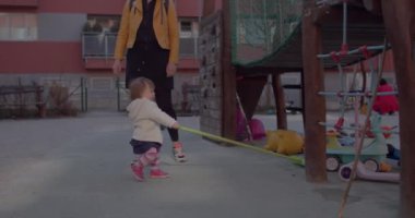 Çocuk parkındaki çocuklu kadın. Küçük kız temizlik malzemesi kullanmaya çalışıyor..