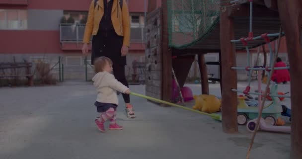 Mujer con niño en el patio. Niña está tratando de utilizar la herramienta de limpieza. — Vídeo de stock