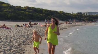 Woman with a child while jogging along the sandy seashore.