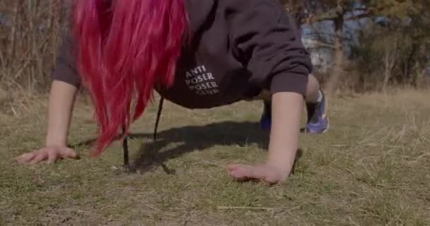 Red-haired woman doing push-ups ground. She bends and unbends arms elbows — Stock Video
