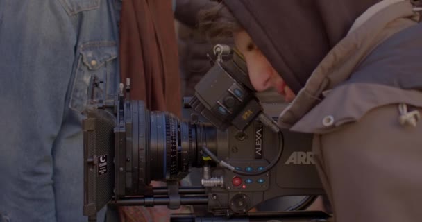 Using optics in a movie camera to shoot video. The specialist views the picture — Stock Video