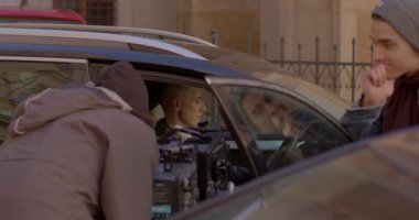 The man is sitting in the car. Shooting a video clip, operators back. 