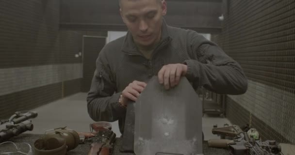 Mężczyzna demonstruje metalową płytkę z kamizelki kuloodpornej trzy kule na płycie — Wideo stockowe