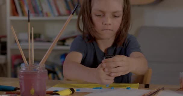 Long hair teenager draws paint sheet paper He takes brush hand smears paint — Stock Video