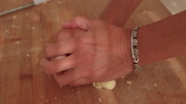 Hands knead the dough on a wooden board. She presses the ball with her hands. — Wideo stockowe