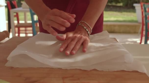 Κάνοντας βάση πίτας χρησιμοποιώντας χαρτί ψησίματος για να κρατήσει τη ζύμη από το να κολλήσει στο πλάστη. — Αρχείο Βίντεο