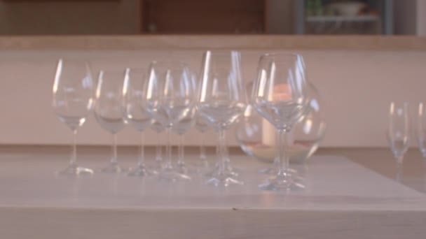 Veel schone wijnglazen op tafel. Feestje klaar. Gerechten gieten drank mensen. — Stockvideo