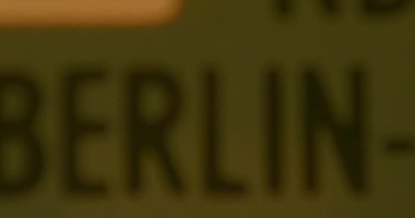 Berlin 'e yakın bir kelime, sarı yüzeyde yazılı. Odaklanma hareketi, pislik, parmaklar.