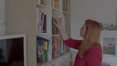 Kadın kütüphanesinden bir kitap seçiyor. Kitap koleksiyonunuzu düzenlemek için yollar