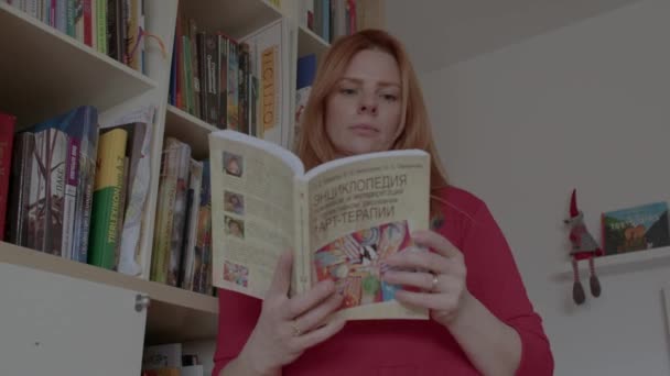 Kvinde med bog om kunsthistorie på russisk fra hendes hjem bibliotek. – Stock-video