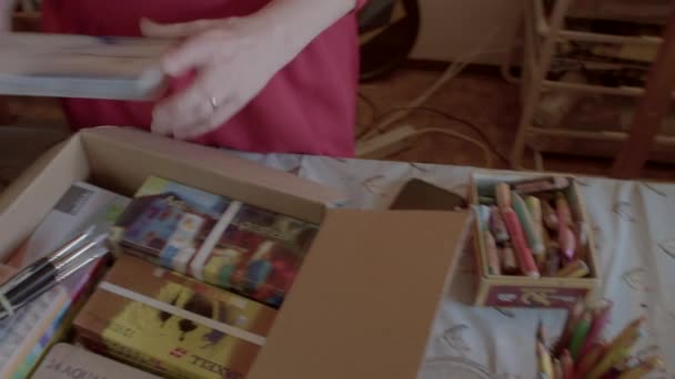 Mãos de terapeuta de arte demonstra doado para refugiados suprimentos de arte em caixas. — Vídeo de Stock