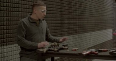 Erkek antrenör atış poligonunu açıklıyor. Güvenlik tekniklerinden bahsediyor.