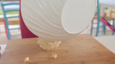 Aşçının elleri, hamuru tabaktan ahşap bir tahtaya koydu..