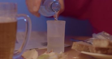 Adam bardağa alkollü sıvı döküyor. El ele tutuşur..