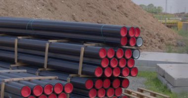 Kırmızı bujili siyah borular için depo. İnşaat malzemelerinin iş yerinde kullanılması için sokakta depolanması. Prizler içerideki boruyu korur..