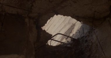 İnşaat sırasında bir binanın beton zemininde büyük bir delik. Metal parçalar öne çıkıyor. Mühendislik objesi hasarı onarıyor. Işık karanlık hasarı vuruyor.