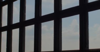 Kafes siluetinin gökyüzüne doğru hareketi. Uzayın kısıtlanması, içeri hava ve ışık girmesi. Bar inşaatı, kare bölüm.