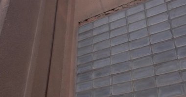 Eski bir hapishanenin cam bloklarından yapılmış bir pencere monte edilmiş mavi bir pencere, duvarda bir vana. Işığın odaya girdiği nokta. Kamera döndürmesi.