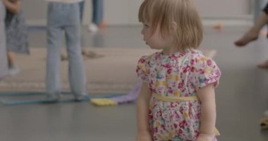 Küçük kız hulahop kullanmaya çalışıyor. Beden eğitimi ve spor odaklı çocuk etkinlikleri organizasyonu.