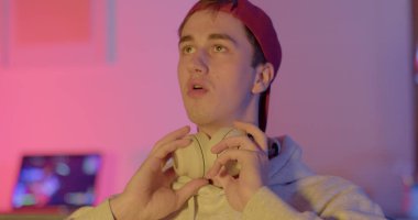 Uzun bir video oyunundan sonra bir oyuncunun yorgun yüzü. Kulaklıklarını çıkartıyor, nefes alıyor, dikkatini topluyor. O, elleriyle gözlerini ovuşturur. Yumuşak odaklanma. Akşam odası..