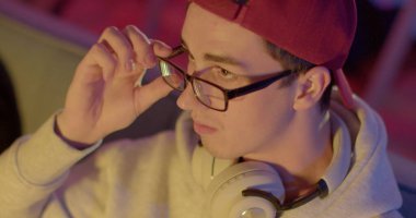 Vizyon rahatsızlığı. Portreci gözlük takar ve video oyunu kumandası kullanır. Gözün dikkati, yakın plan. Akşamları evde boş zaman aktiviteleri. CZ, Prag, Plzenska, 20.6.2022