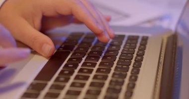 İşçiler dizüstü bilgisayarın klavye tuşlarını kullanır. Tıklamalar, metin dosyası seti. Düz sıra düğmeler. Bokeh meydanında halka var. Odada akşam ışığı.