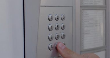 Bir parmağın yakın çekimi dahili haberleşme düğmelerine basar. Kapıyı açmak için daireye uzaktan arama. Bir misafir geldiğinde bildirim kullan.