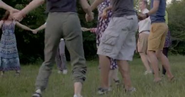 Yuvarlak dansta dans eden insanların hareketi. Tarihi bir ayin yapıyorlar. Bacaklar adım atar. Şort giy, ayakkabılar ayaklarını koru. Tarlada yeşil çimen. CZ, Prag, Hostovar, 4.7.22