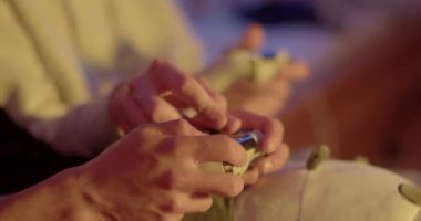 Maçta elle antrenman. Oyuncuların kontrolörlerle yakın çekimi. Düğmeye basıyorlar, karakter kontrolü yapıyorlar. İnsan eli bastırmaya yardımcı olur. Hafta sonları boş zaman aktiviteleri.