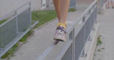 Bacaklı ergen avlu boyunca yürüyor. Adımlarını dengede tutuyor. Koordinasyon ve denge eğitimi. Aşağı doğru atlıyor. CZ, Kladno, Polska, 4.7.22