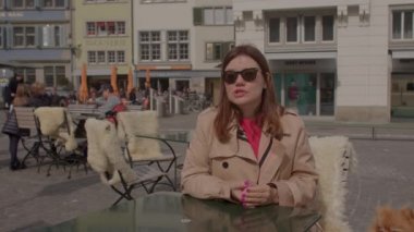 Kadın bir sokak kafesinin masasında oturarak konuşuyor. Basına önemli bir konu hakkında yorum yapın, fikrinizi belirtin. Müze, Zürih, İsviçre, 10.03.2022