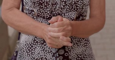 Yaşlı bir kadının elleri, parmaklarına masaj yapar. Parmaklarını ovuyor, eklemleri ısınıyor. Parmağında yüzük var. Canlı duygular, vücut dili.